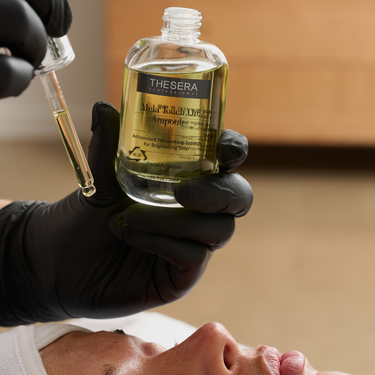 esthetician dropping skincare serum onto client's skin 